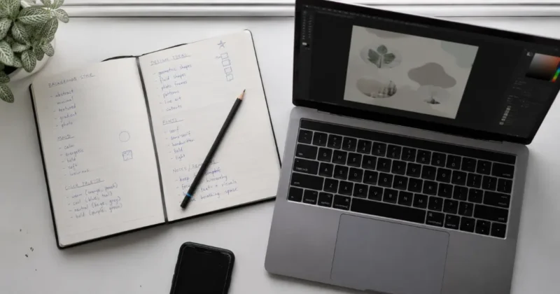 Handwritten prompting notes for Canva Magic Media image generation beside a laptop canvas